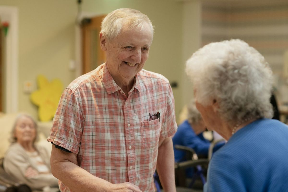 Two older women sharing a laugh in a common room